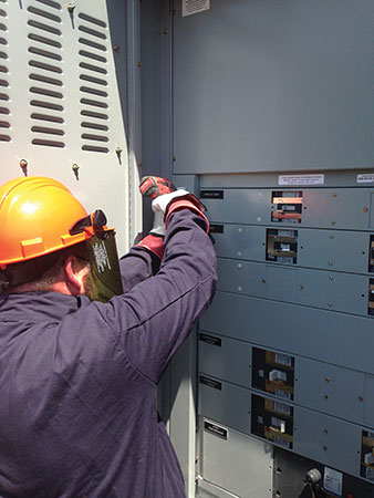 Photo 1. An electrical inspector wearing proper PPE for the incident energy available inspects this electrical equipment. Even inspectors need to dress for success and adhere to the requirements of NFPA 70E.