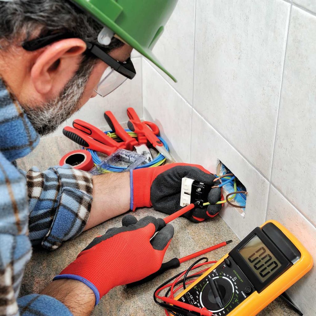 Photo 1. Electrical worker is wearing a hard hat, safety glasses, and protective gloves is using insulated tools to install a receptacle. Is he practicing safe work habits?