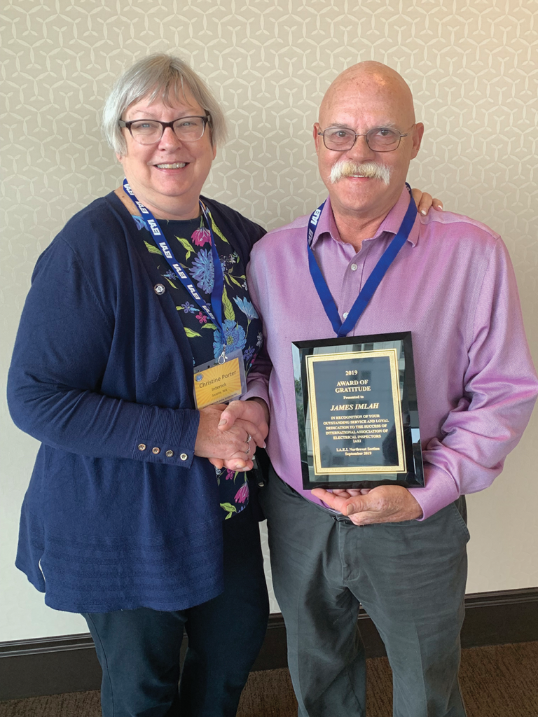 IAEI Northwestern Board Member and CMP-5 Principal Christine Porter congratulating James Imlah with a 2019 Award of Gratitude plaque at the Northwestern Section meeting.