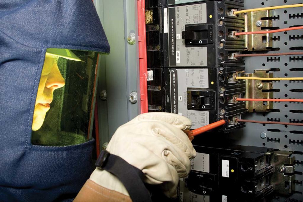 Electrician wearing PPE Equipment per NFPA 70E working on electrical equipment