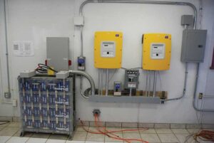 Photo 5. Energy storage system (ESS) as part of a battery-backed-up PV system.  Disconnect circuit breakers are on top of the batteries on the left side of the picture. Courtesy of John Wiles