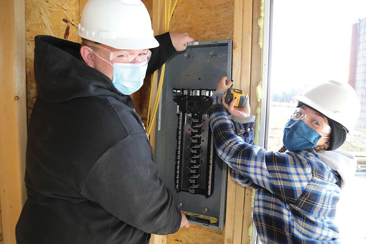 Ulster BOCES Electrical Construction & Maintenance students from Saugerties Central School District, Jonathan Toth (left) and Kaitlyn Lennon work together to hang the electrical panel at the Habitat for Humanity house in Glasco, NY. Photo Courtesy-Kristine Conte/Ulster BOCES